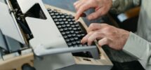 Person skriver på en mekanisk skrivmaskin vid ett skrivbord