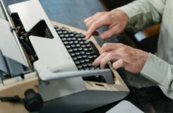 Person skriver på en mekanisk skrivmaskin vid ett skrivbord