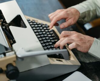 Person skriver på en mekanisk skrivmaskin vid ett skrivbord